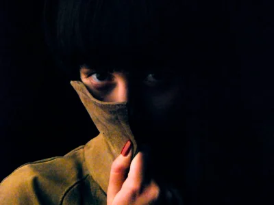 Woman face hidden jacket dark background